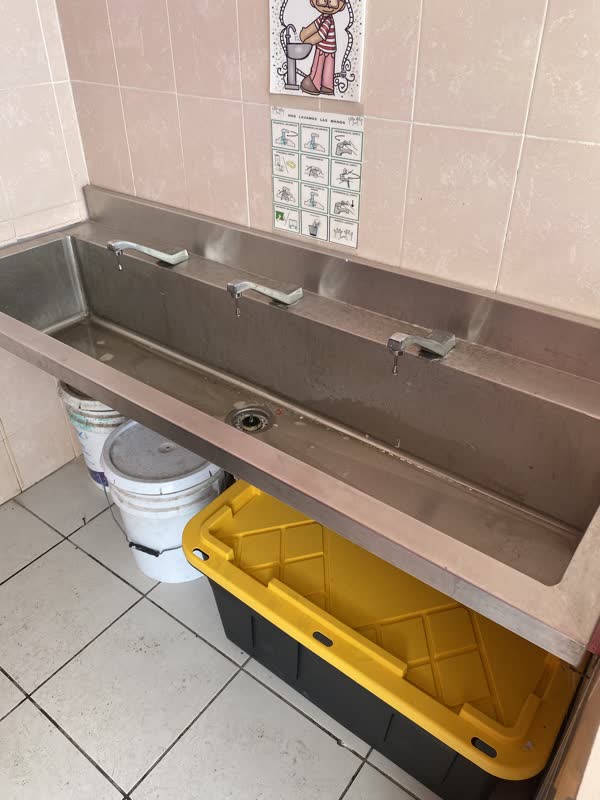 Lavabo corrido de acero inoxidable en baño infantil